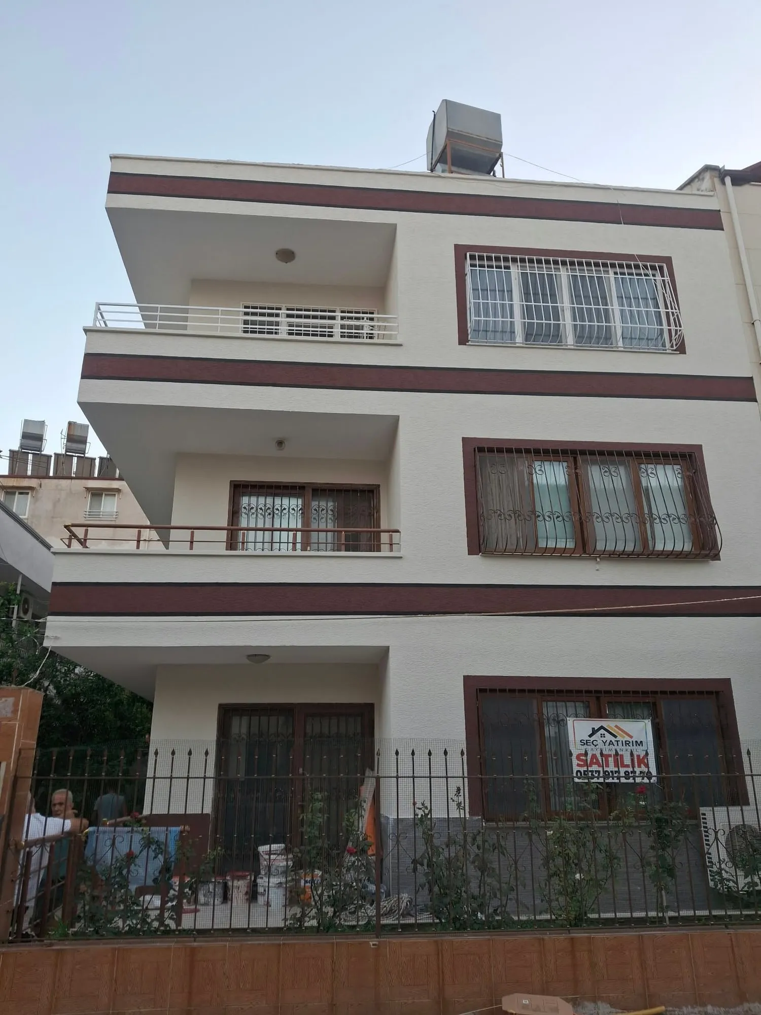 Bordo şeritli beyaz cephesiyle yenilenmiş müstakil bina