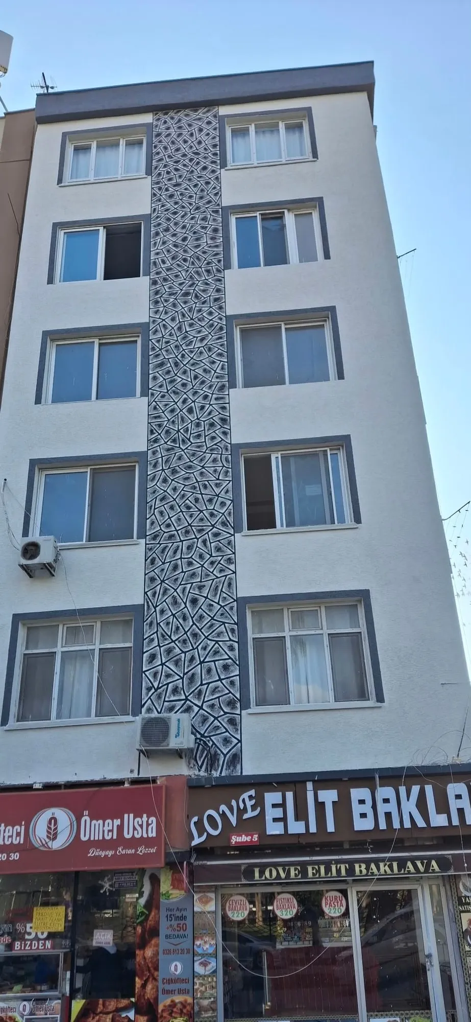 Dış cephesi yenilenmiş çok katlı bina, ortasında dekoratif desenli dikey şerit uygulaması