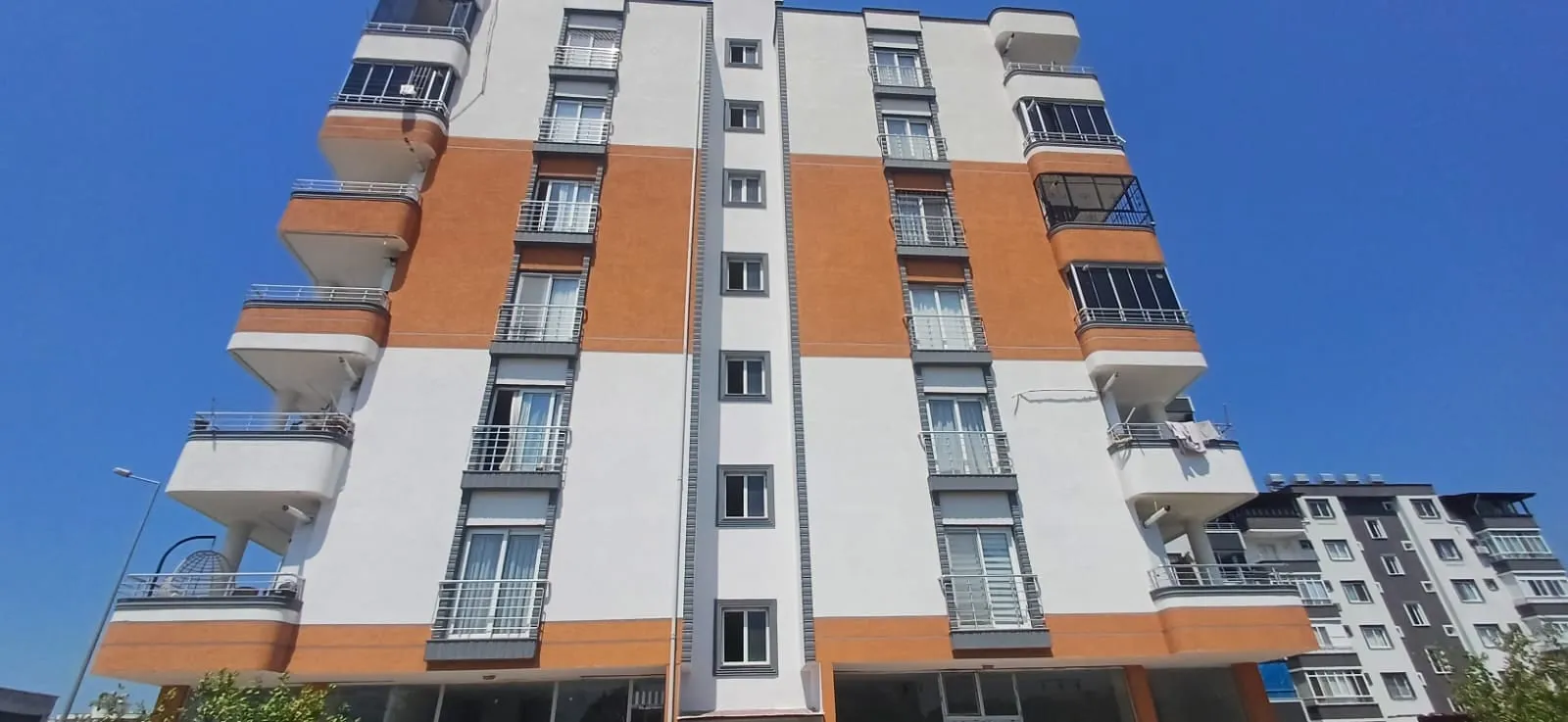 Turuncu ve beyaz bantlarla boyanmış çok katlı bina cephesi